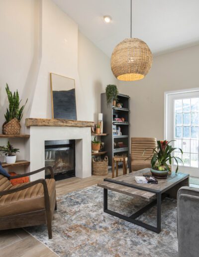 A cozy modern living room with a fireplace, bookshelves, and a mix of comfortable seating.