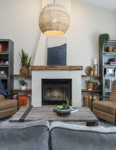 A cozy living room with a fireplace, armchairs, a sofa, and bookshelves.