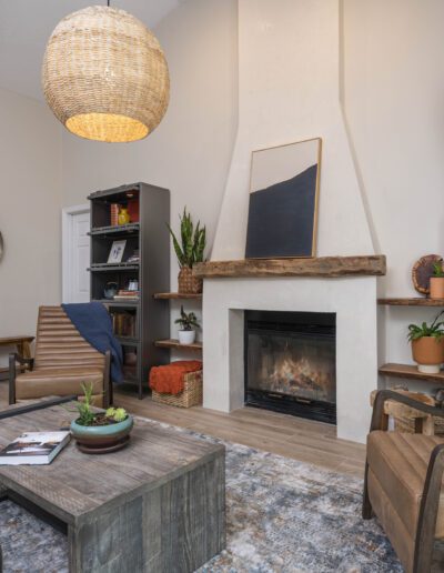 Cozy living room interior with a fireplace, comfortable seating, and decorative shelving.