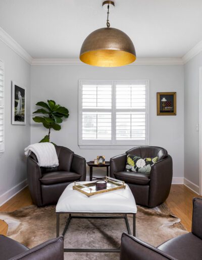 Modern living room with two brown armchairs, a white coffee table, and decorative plants.