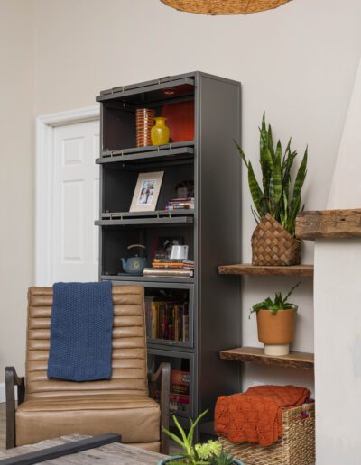 A cozy reading corner with a comfortable chair, a bookcase, and houseplants.