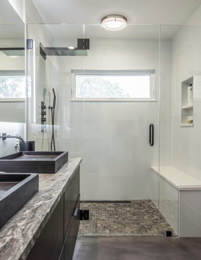 Modern bathroom with dual sinks, a walk-in shower, and neutral color tones.