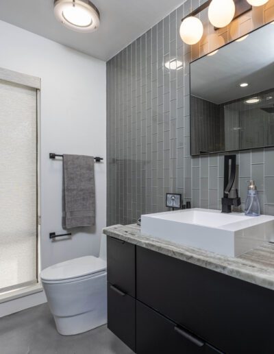 Modern bathroom interior with gray tiles, a black vanity, and sleek fixtures.