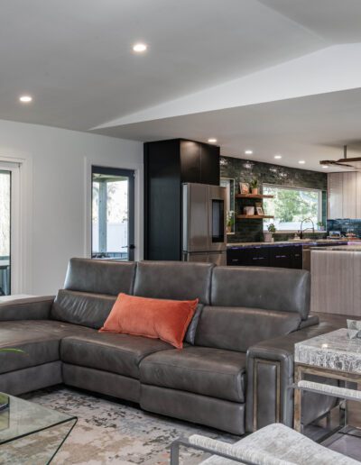 Modern open-concept living room with l-shaped sofa and integrated kitchen in the background.