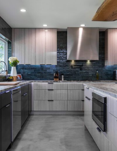 Modern kitchen with stainless steel appliances and blue backsplash tiles.