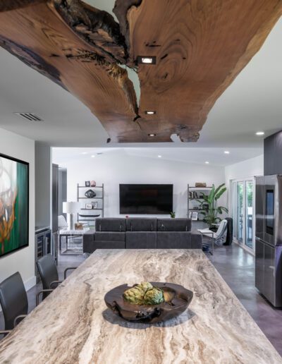 Modern kitchen with a natural wood island countertop and matching artistic wood ceiling feature.