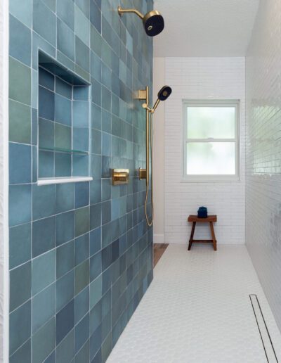 Modern bathroom with blue tiled shower area and white subway tiles.