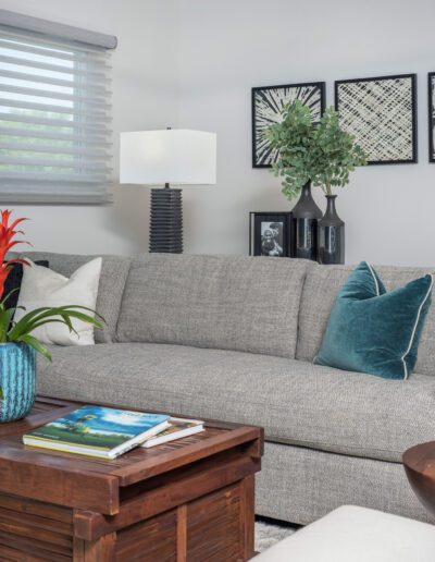 A cozy and modern living room featuring a comfortable gray sofa, a wooden side table, decorative cushions, and wall art.