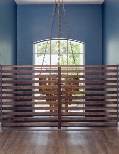 A modern room with a wooden railing, dark blue walls, a hanging light fixture, and a window.