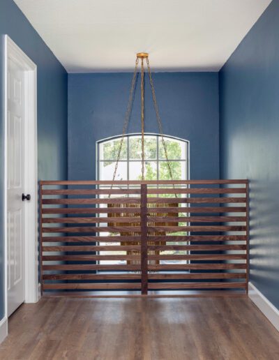 Interior space featuring blue walls, wooden floors, a large window with blinds, and a unique hanging light fixture.