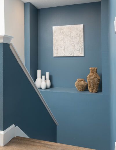 A modern staircase nook with decorative vases and artwork.