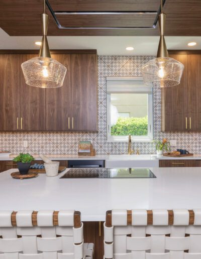 Modern kitchen interior with wooden cabinets, white countertop island, and pendant lighting.