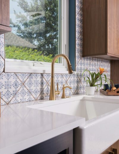 A modern kitchen corner featuring wooden cabinetry, white countertops, and decorative tile backsplash.