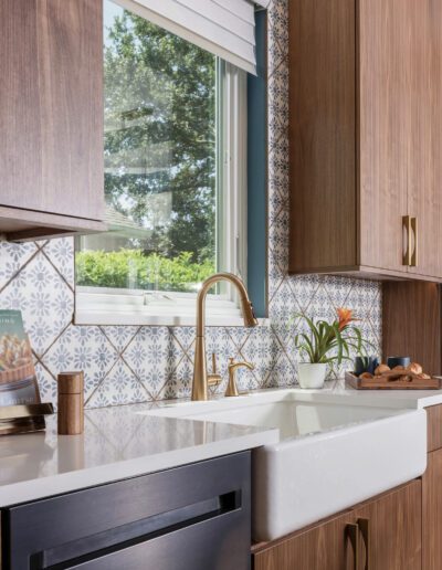 Modern kitchen corner with wooden cabinets, patterned backsplash, and white countertop.