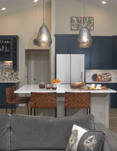 Modern kitchen with navy blue cabinetry, stainless steel appliances, and pendant lighting over an island with seating.