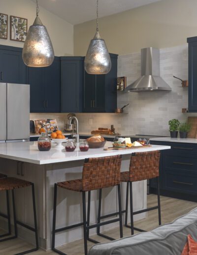 Modern kitchen interior with dark blue cabinets, stainless steel appliances, and a central island with bar stools.