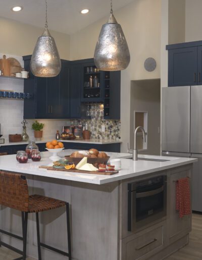 Modern kitchen with blue cabinetry, stainless steel appliances, and an island with seating.