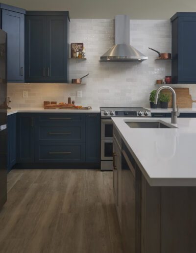 Modern kitchen with navy blue cabinets, stainless steel appliances, and white countertops.