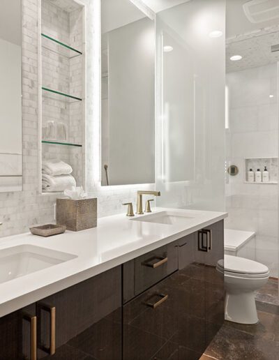 Modern bathroom interior with double vanity and glass-enclosed shower.