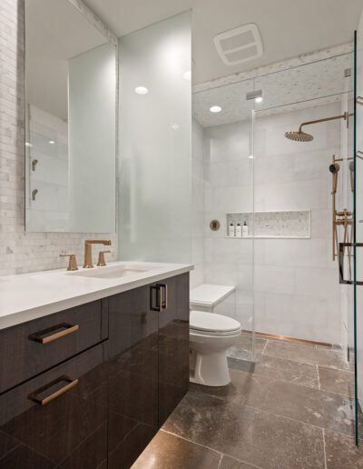 Modern bathroom with double vanity, large mirror, walk-in shower, and white fixtures.