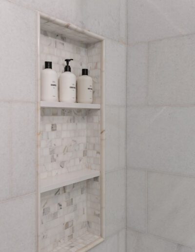 Built-in shower niche with three bottles of bath products.