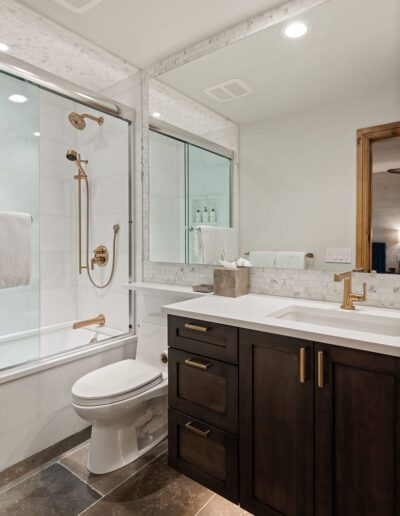 Modern bathroom interior featuring a glass-enclosed shower, dark wood vanity with white countertop, and toilet.