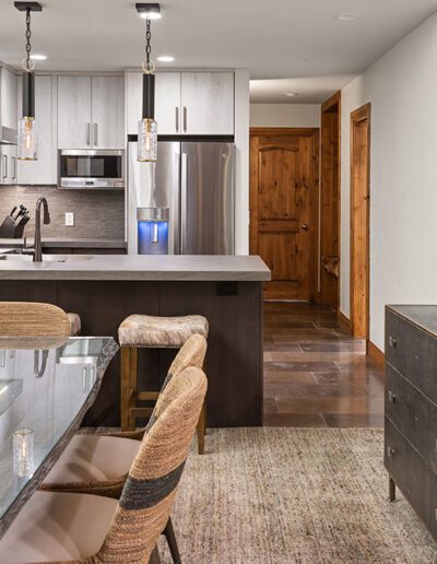 Modern kitchen interior with a glass dining table and stainless steel appliances.