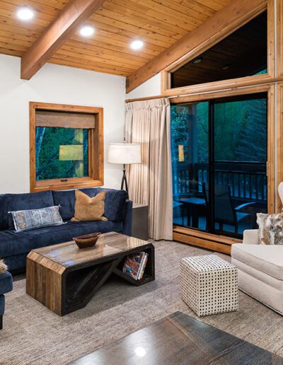 Cozy living room with modern furniture and large windows showcasing a forest view.